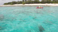 Two people in a canoe on a clear blue ocean.