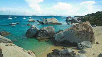 A rocky beach with boats in the water.