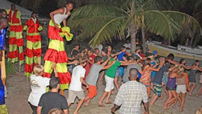 A group of people on stilts on a beach.