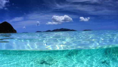 A clear blue ocean with mountains in the background.