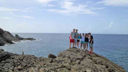 A group of people standing on top of a rocky cliff.