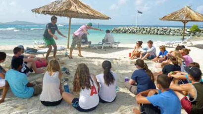 A group of people sitting on the sand on a beach.