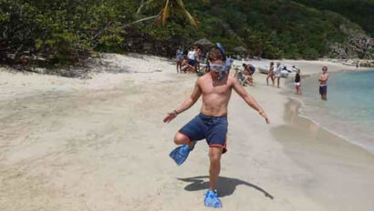 A man wearing snorkling gear on a beach.
