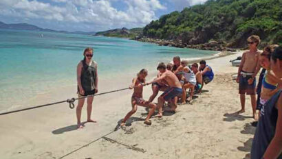 A group of people on a beach pulling a rope.