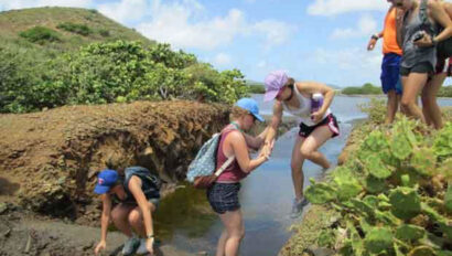 A group of people standing on a muddy bank.