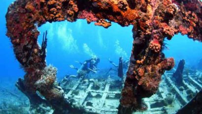 A scuba diver swims around a wrecked ship.
