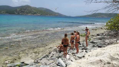 A group of people standing on a rocky beach near the ocean.