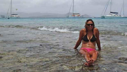 A woman in a bikini laying in the shallow water.