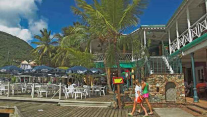 A group of people walking along a dock in front of a restaurant.