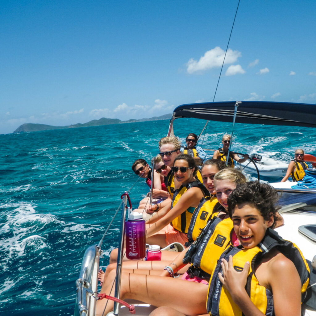 A group of people on a sailboat in the ocean.