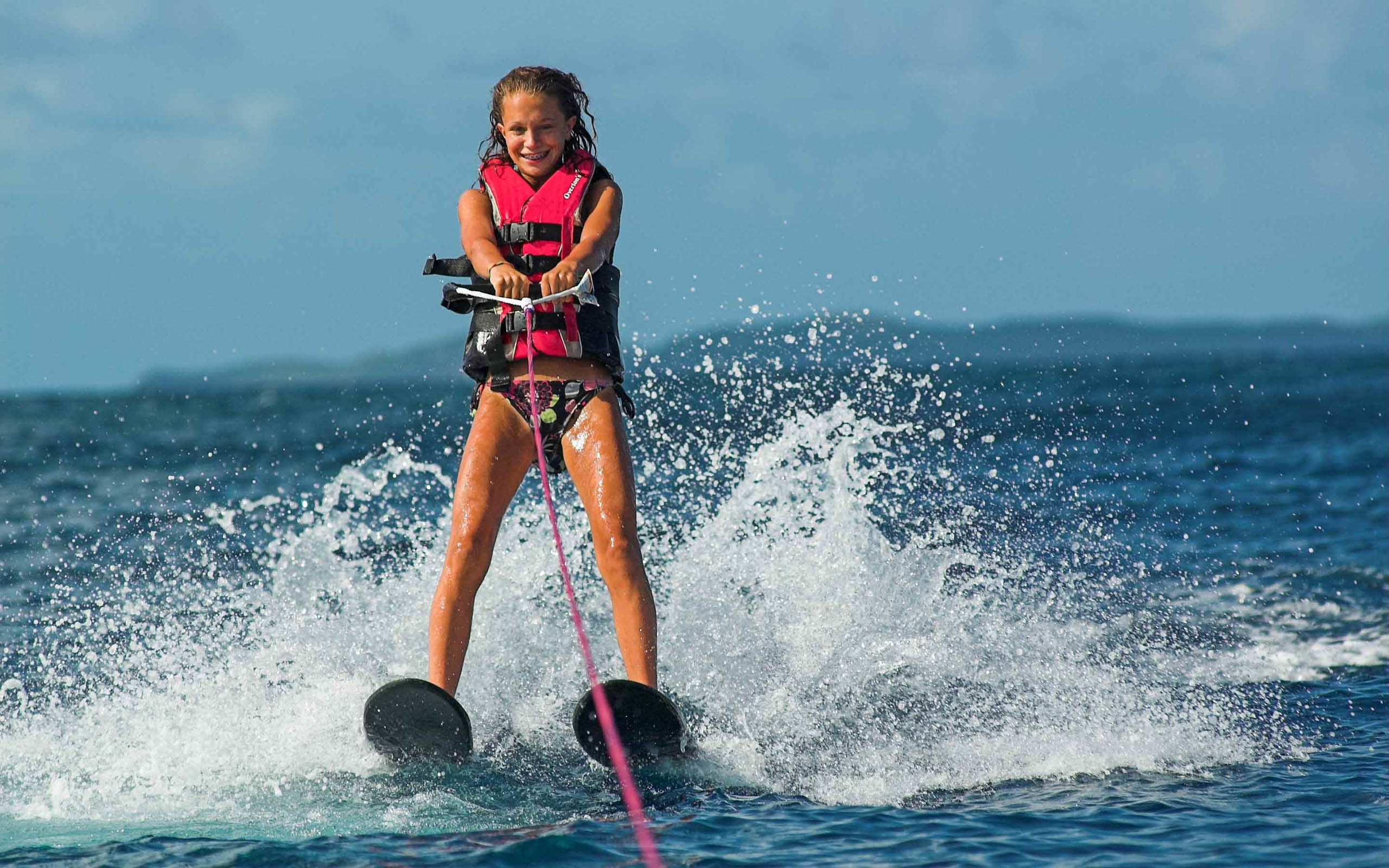A girl in a life jacket on water skis.