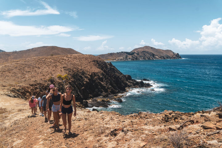 A group of people walking on a trail near the ocean.
