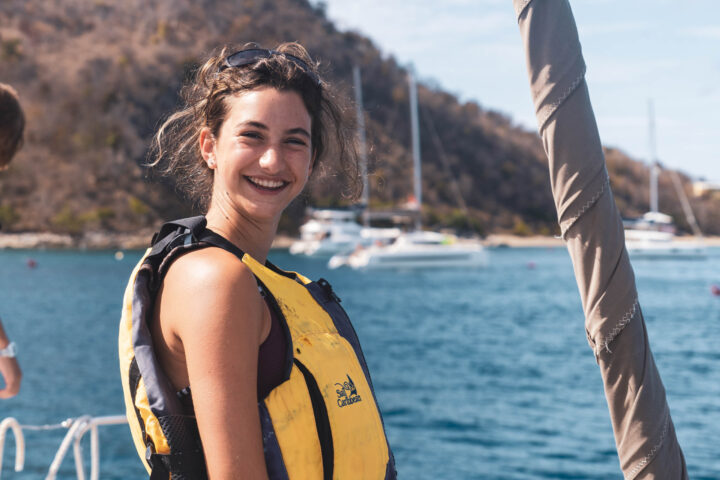 A woman in a yellow life jacket on a boat.
