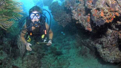 A scuba diver in a scuba gear near a coral reef.