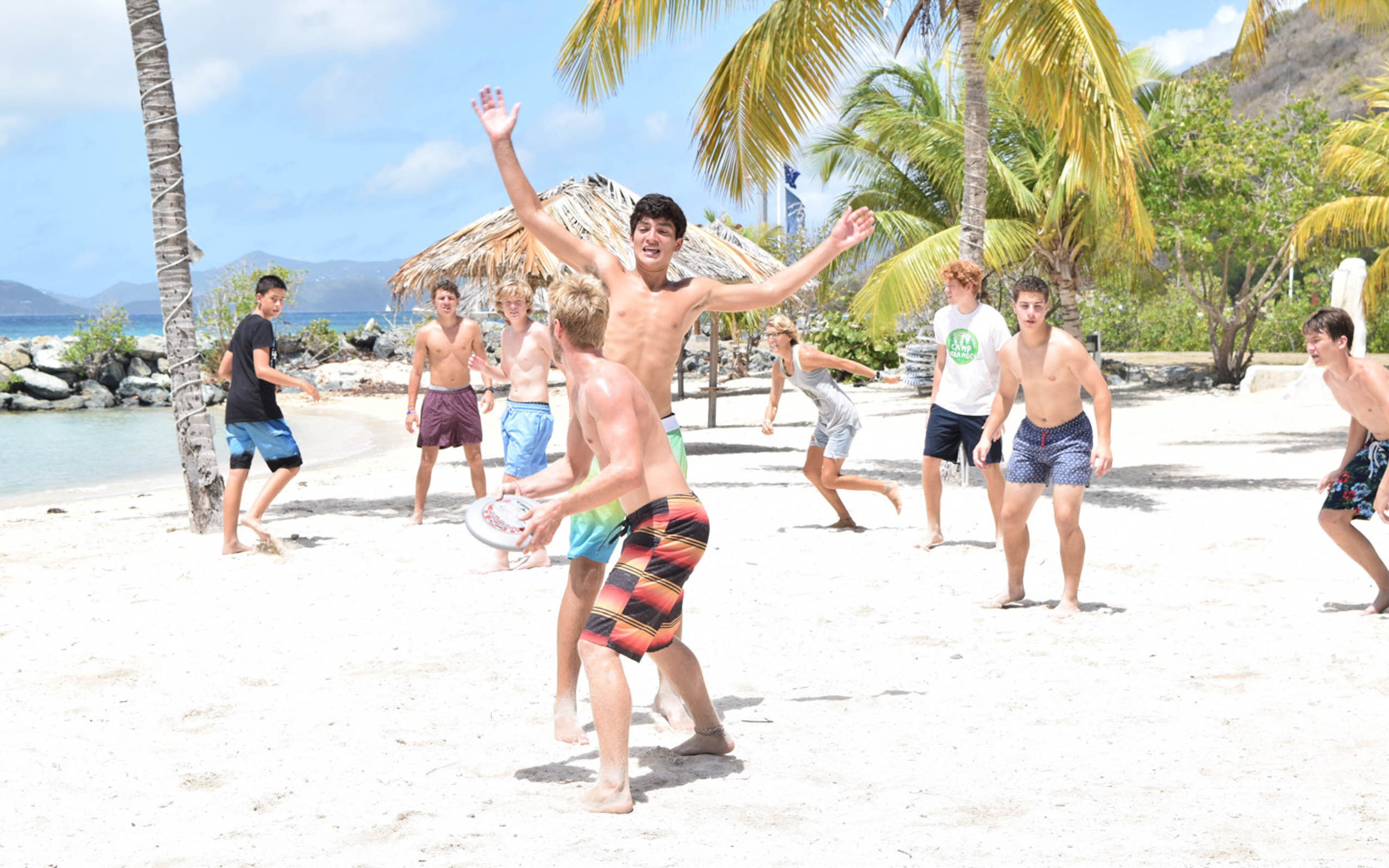 A group of boys playing frisbee on a beach.