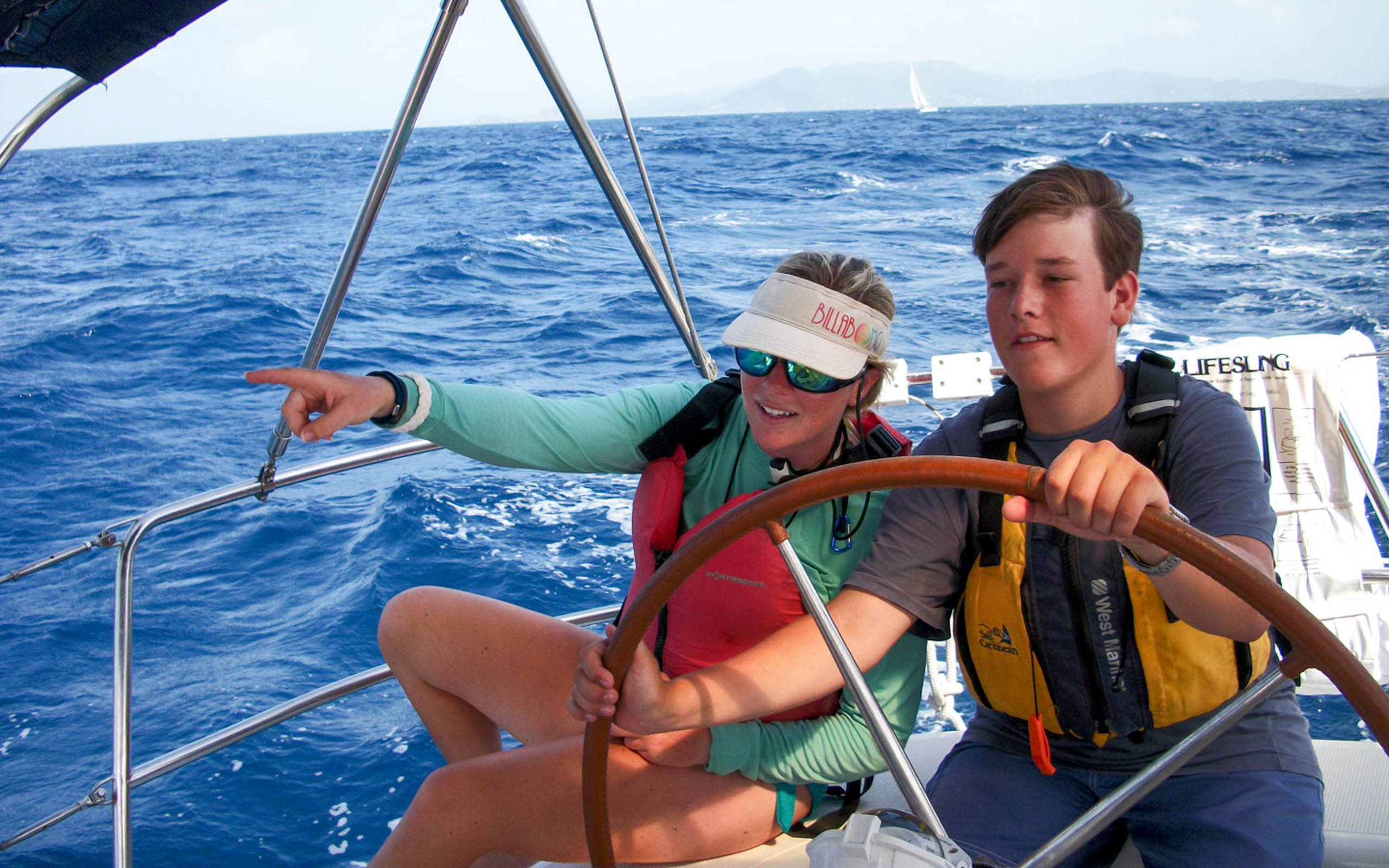 Two people on a sailboat in the ocean.