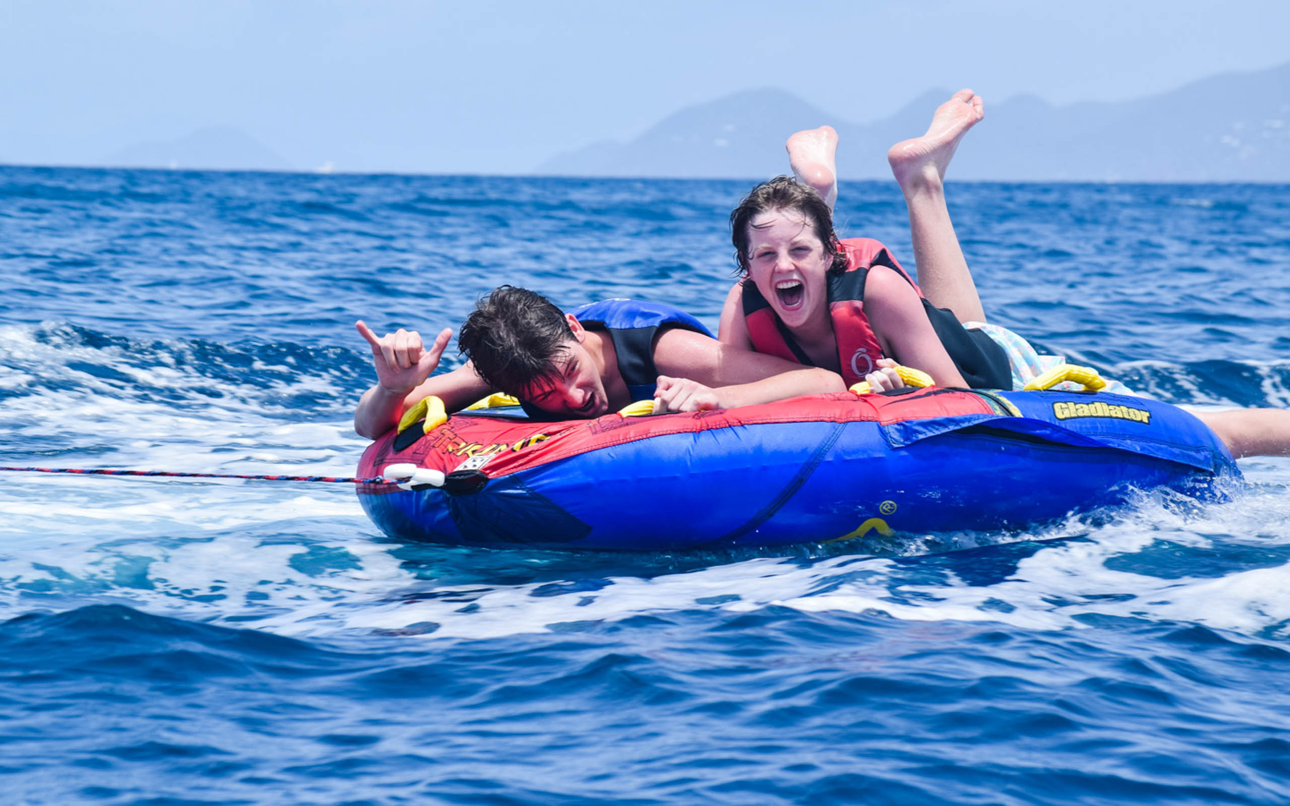 Two people riding on an inflatable tube in the ocean.