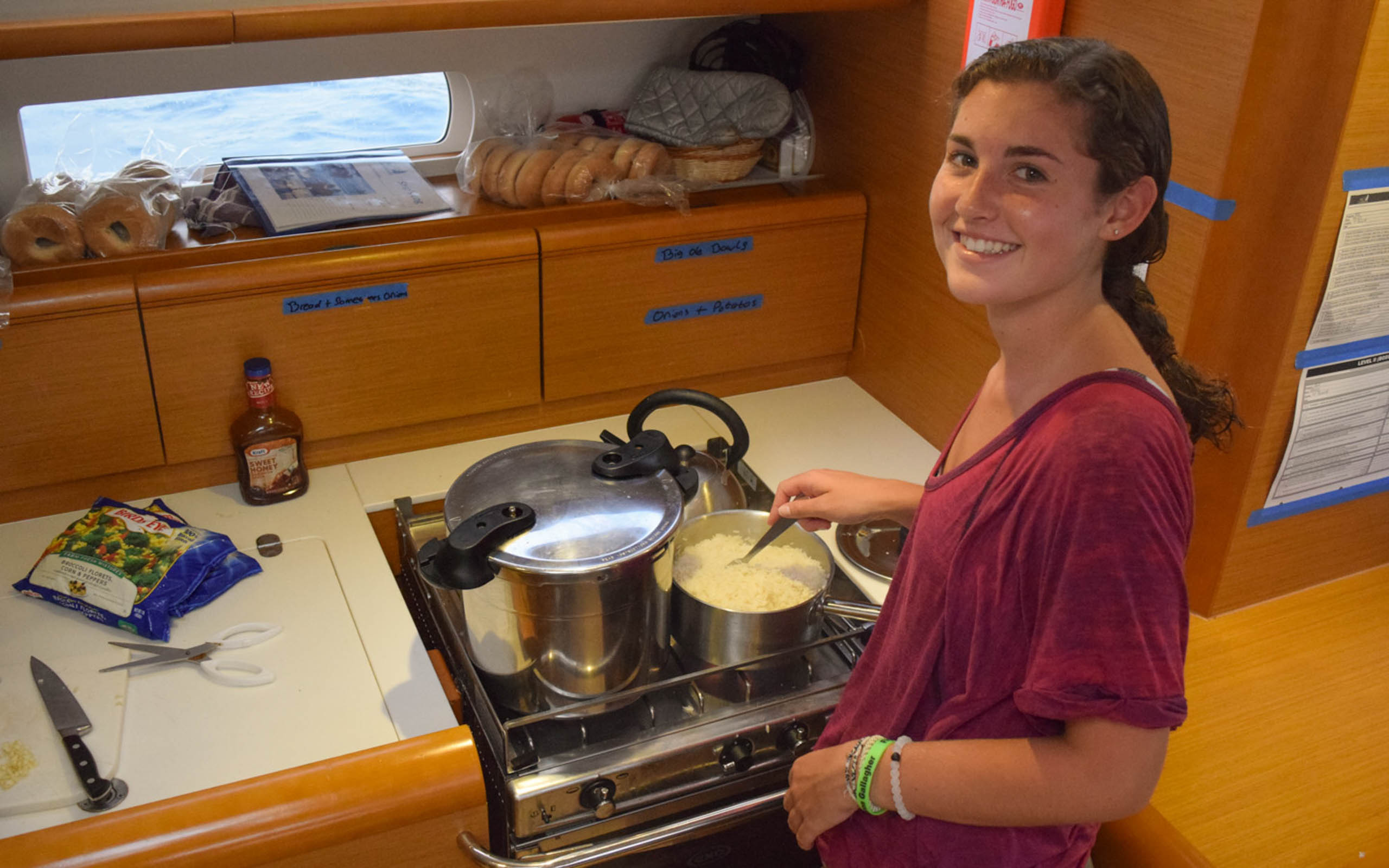 A young woman cooking in a kitchen on a boat.