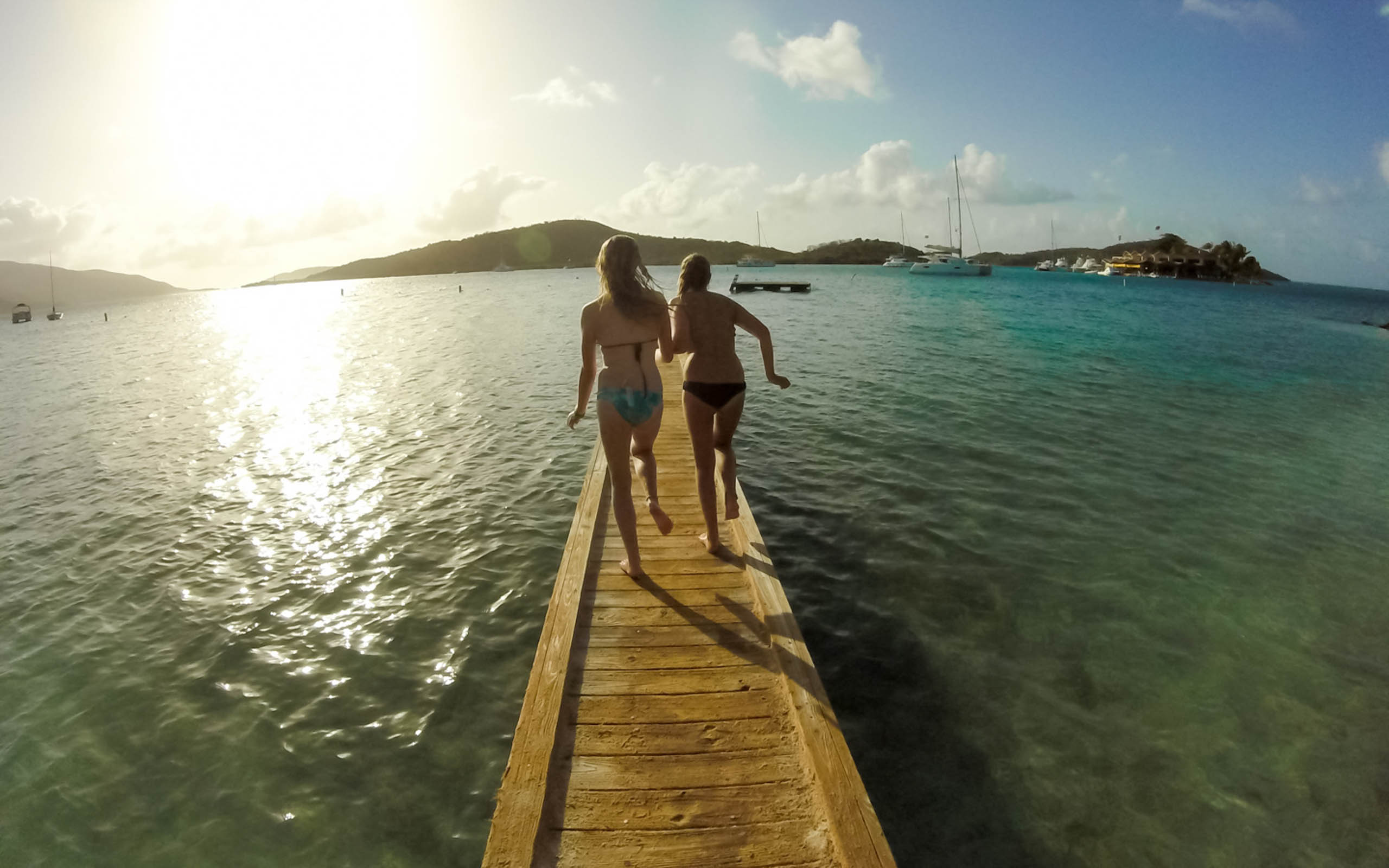 Two people walking on a dock in the water.