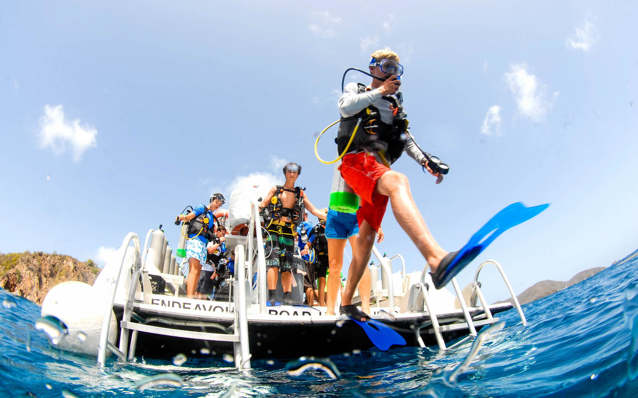 A group of people scuba diving on a boat.