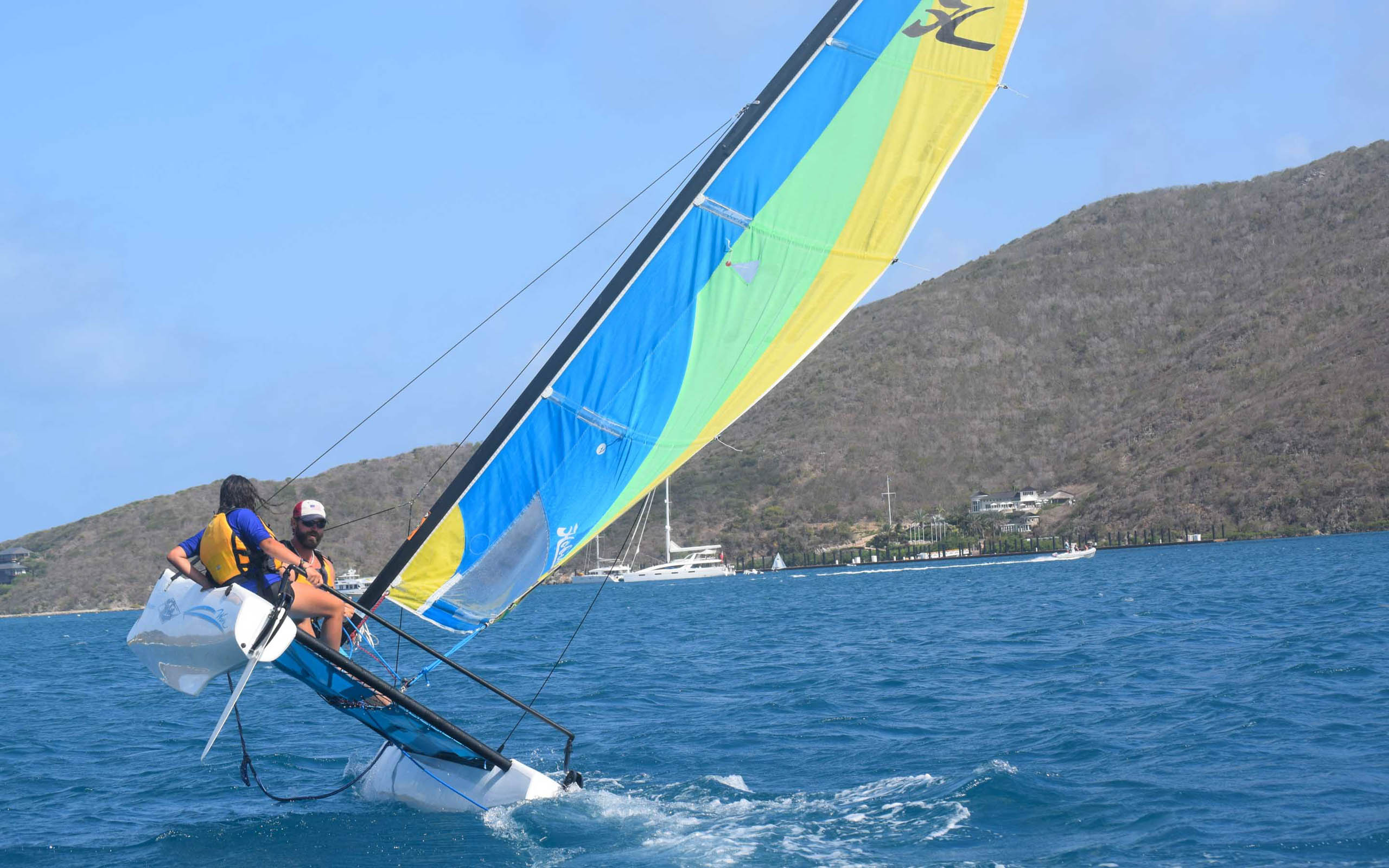 Two people sailing a sailboat in the ocean.