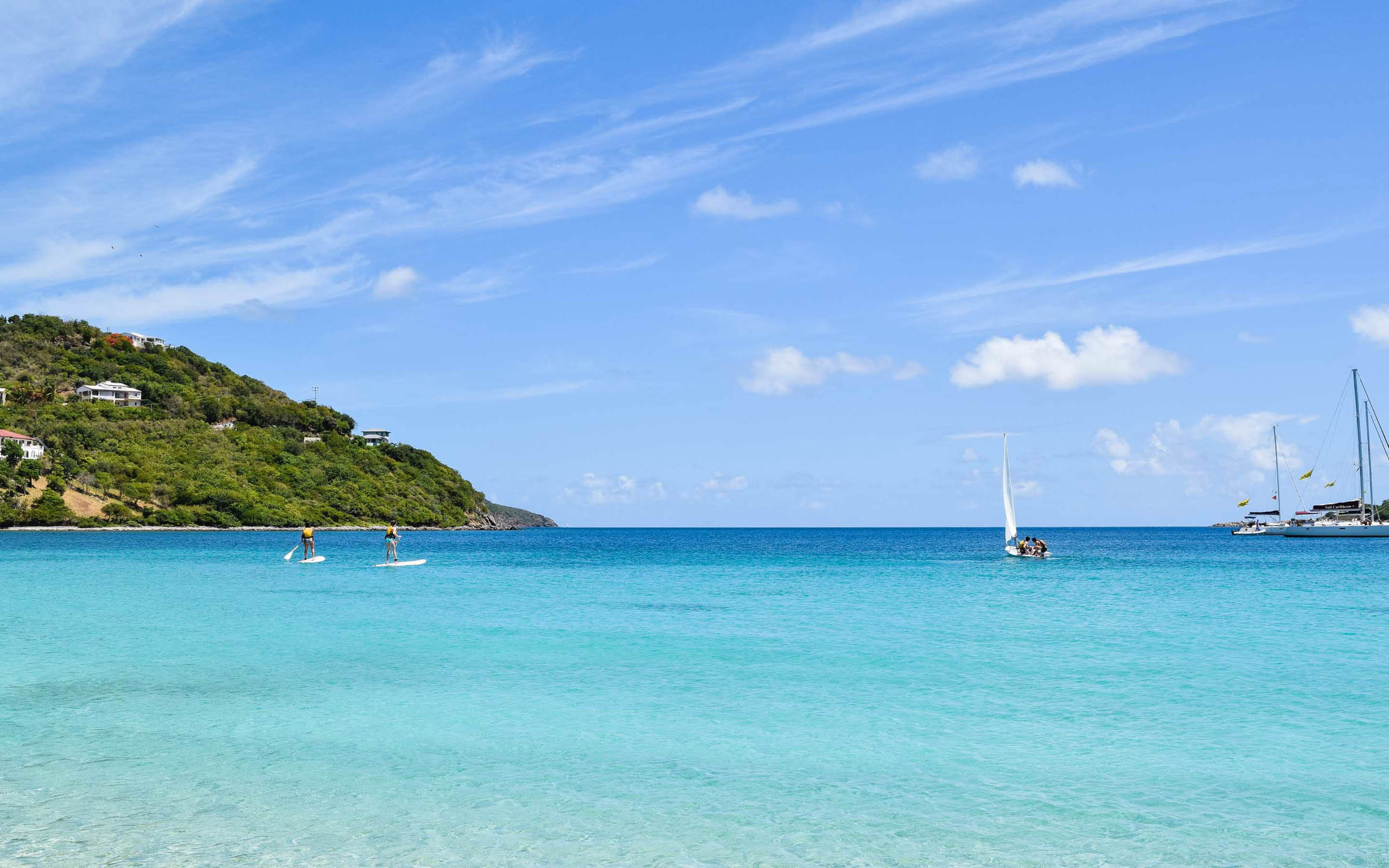 A group of sailboats on a beach near a hill.