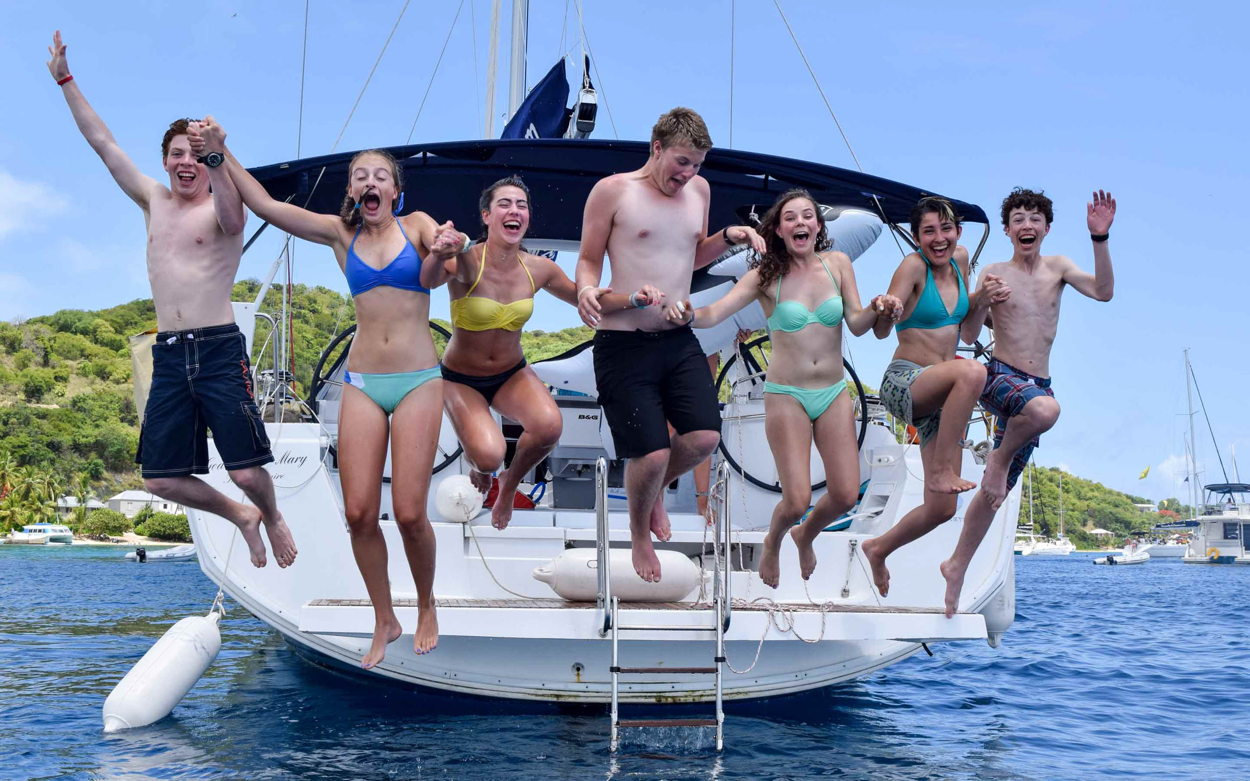 A group of people jumping on a sailboat.