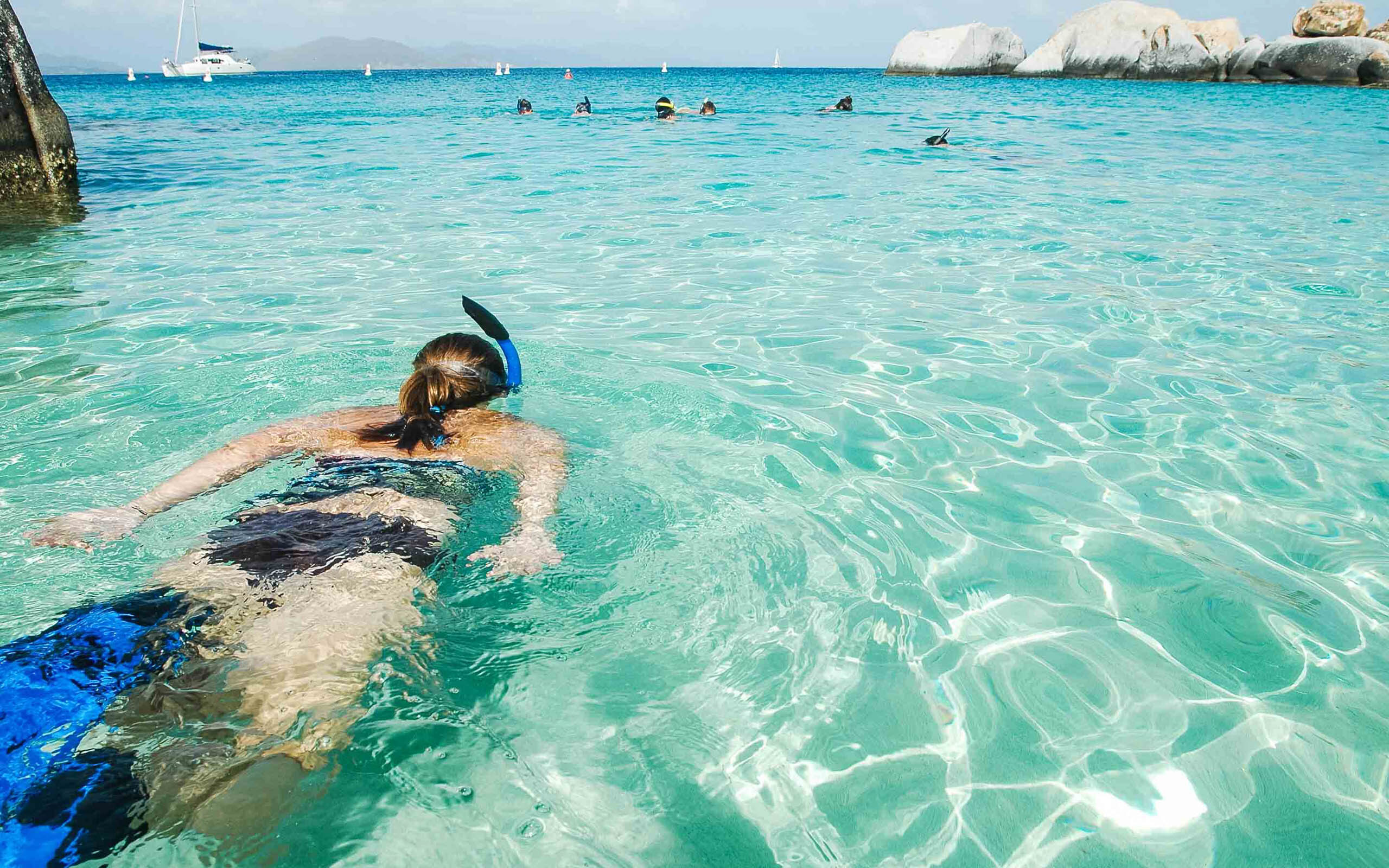 A woman snorkling in the clear blue water.