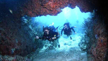 Scuba divers under a cave.