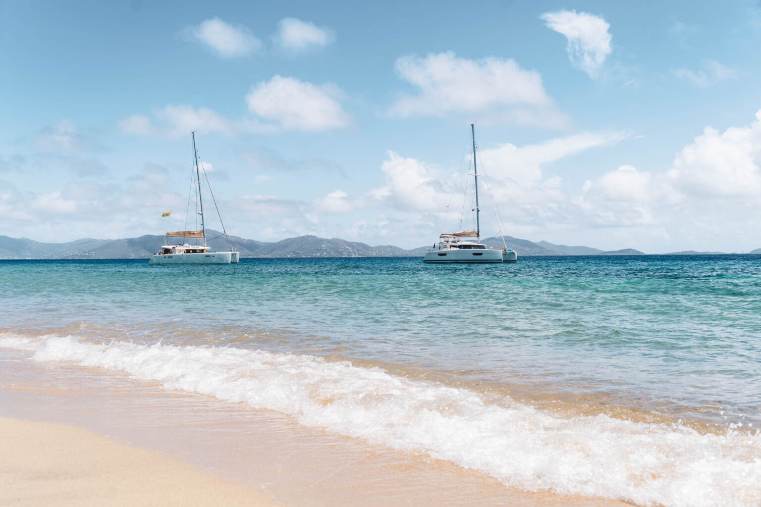 Two sailboats on a beach in the caribbean.