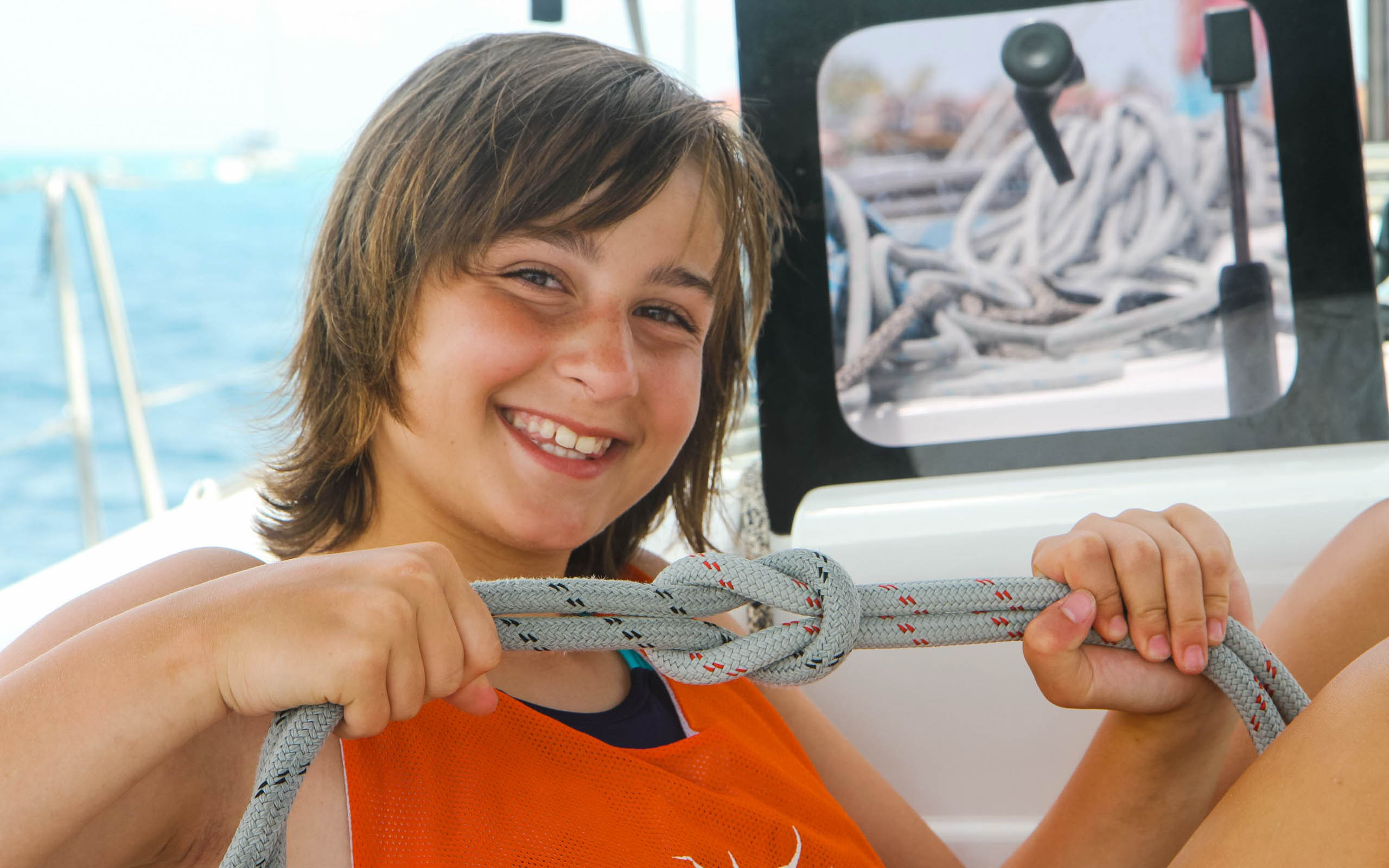A boy holding a rope on a boat.