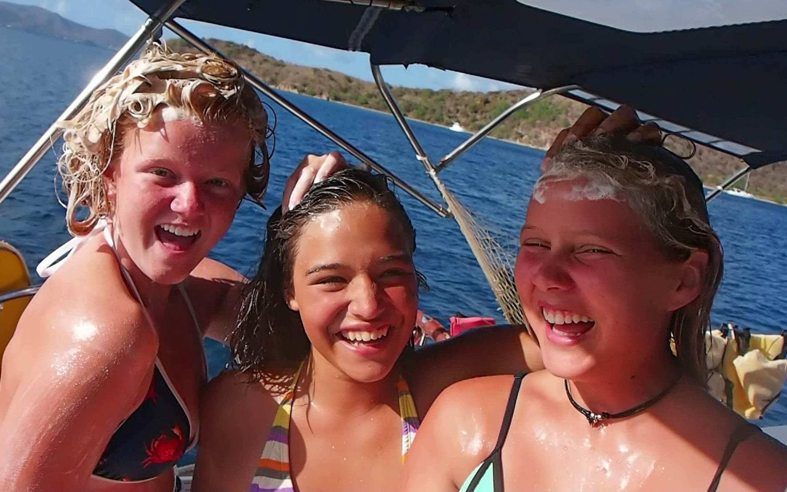 Three girls on a boat with their hair wet.