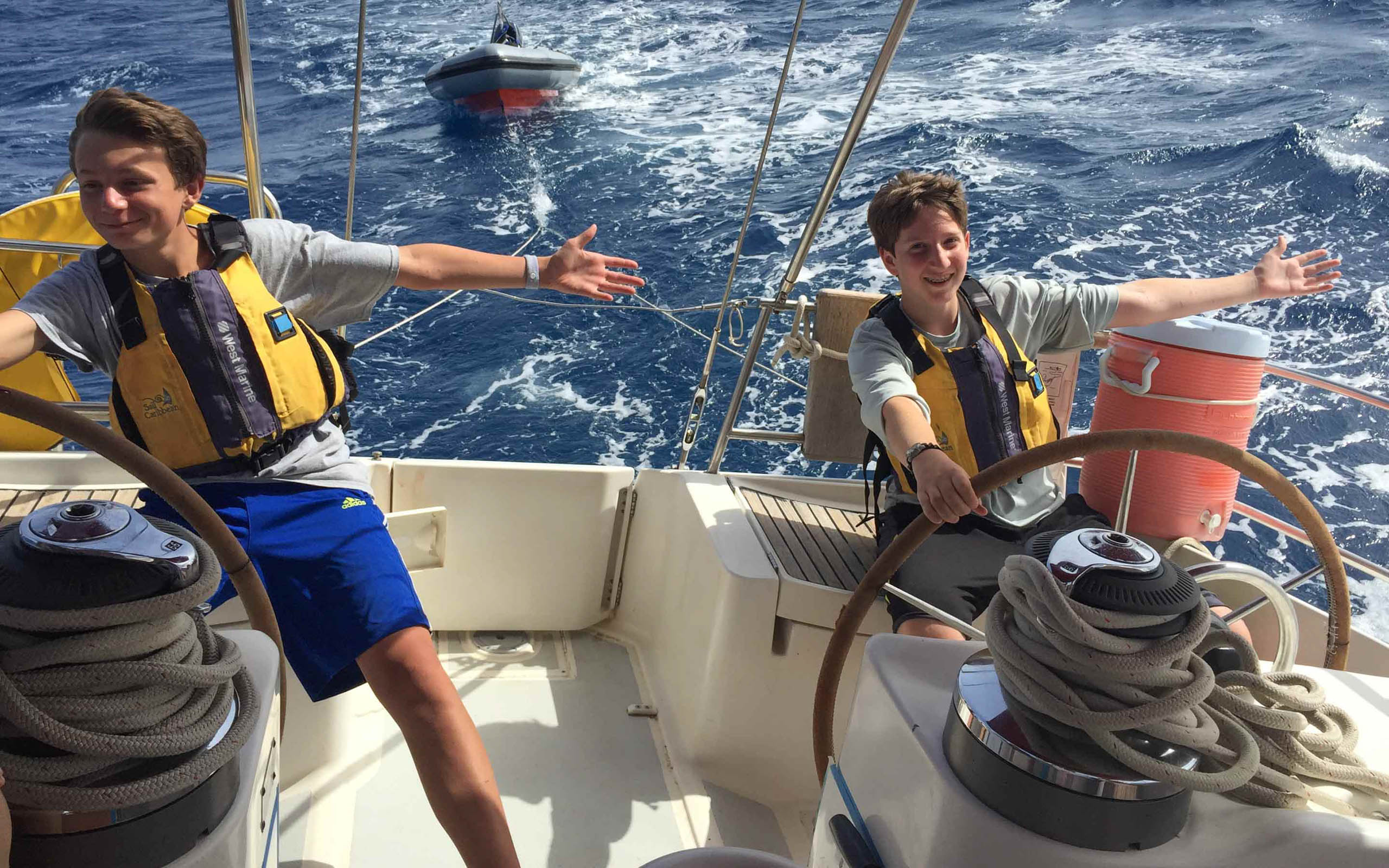 Two boys on a sailboat in the ocean.