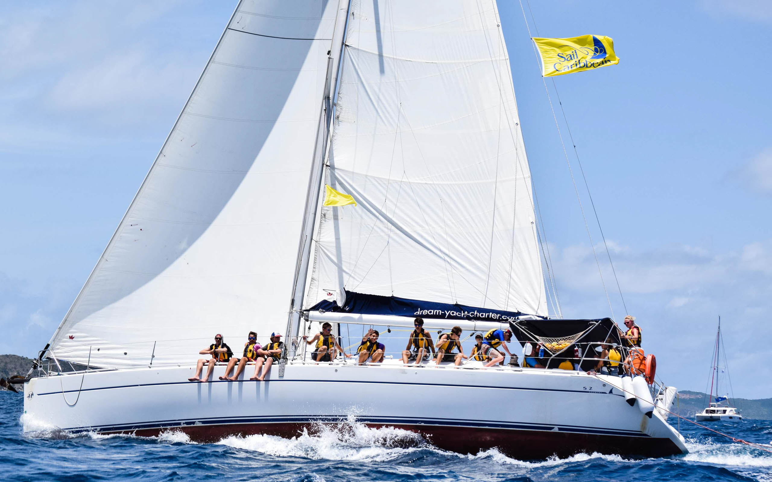 A group of people on a white sailboat in the ocean.