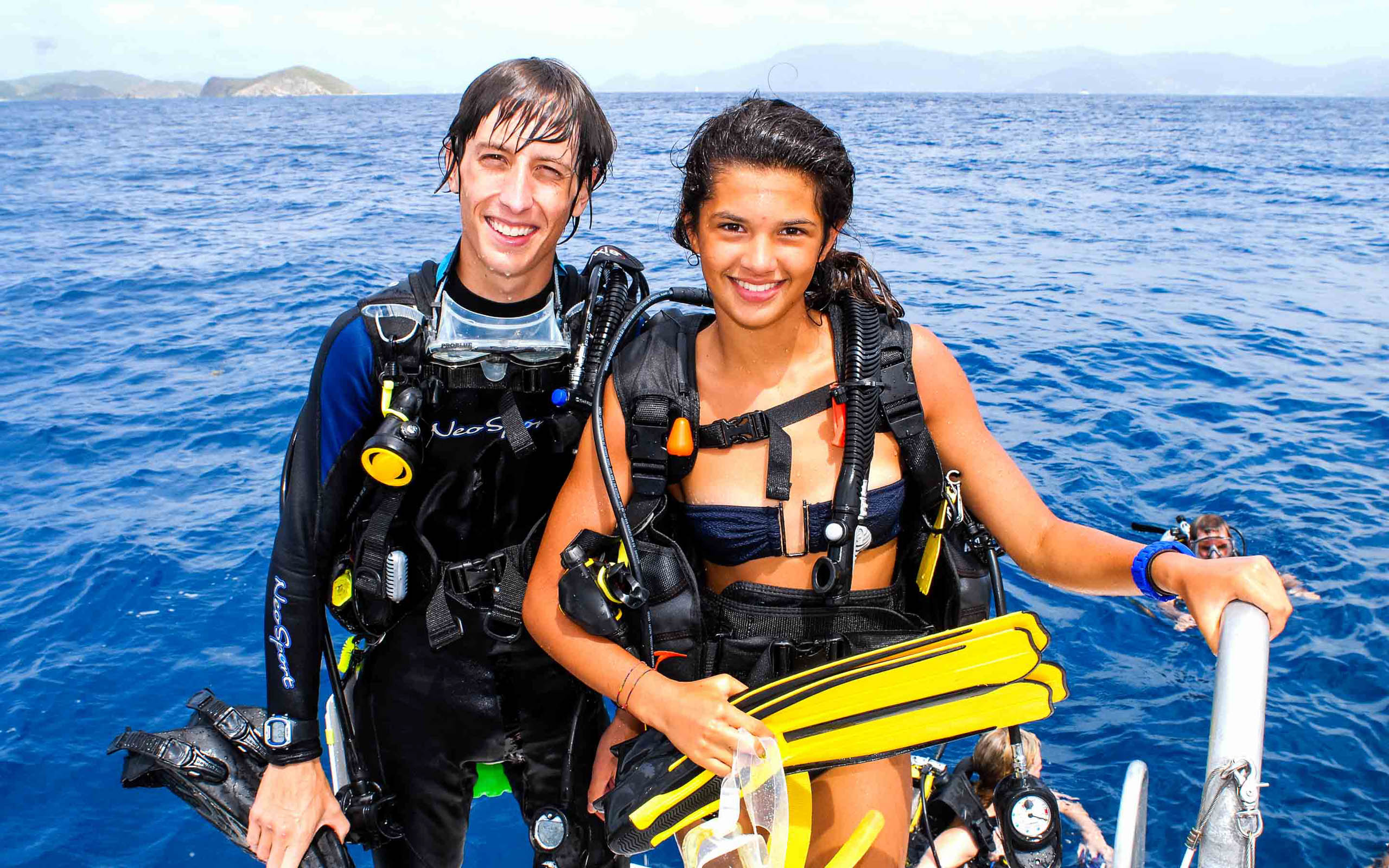 A man and woman scuba diving on a boat.