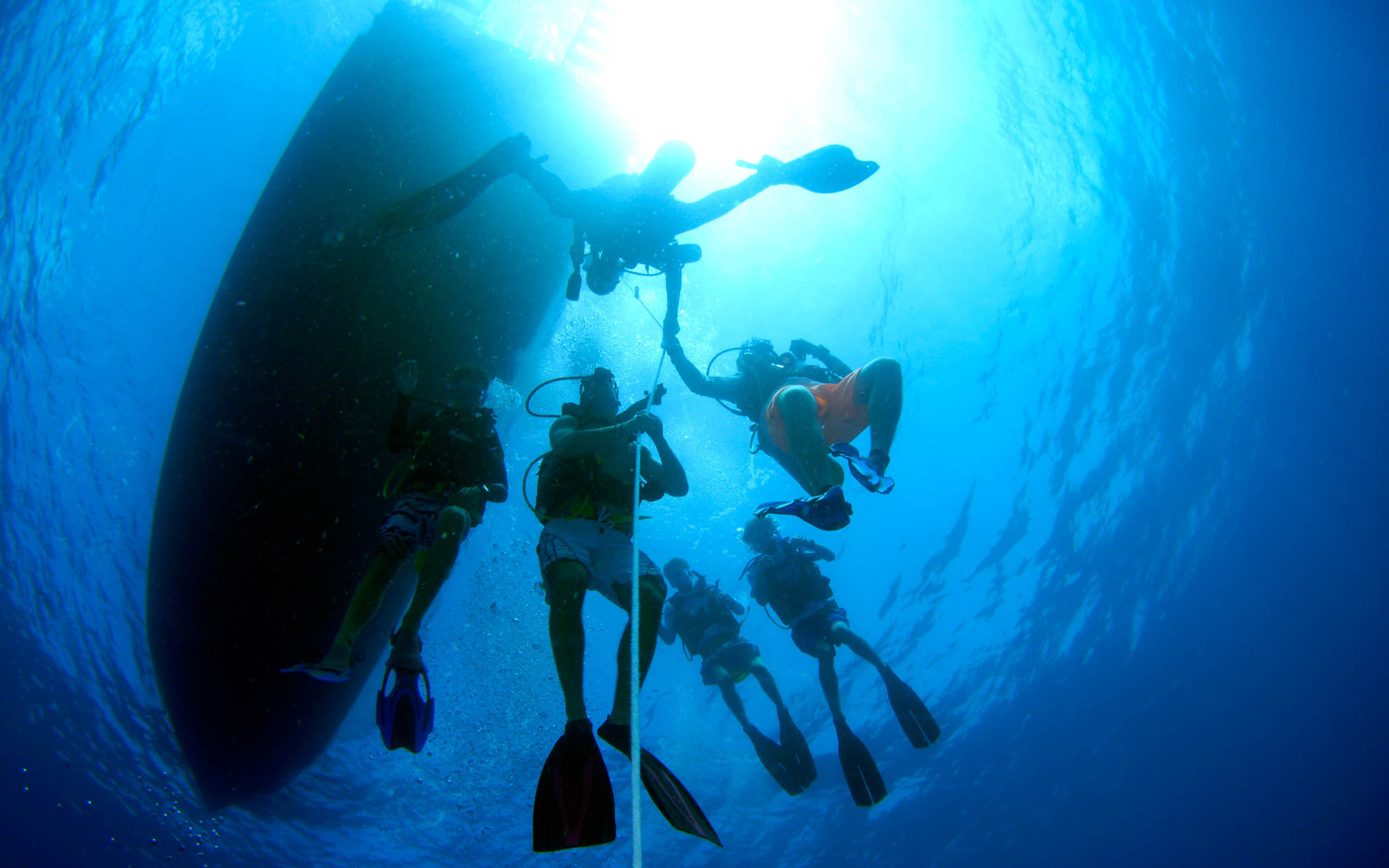 A group of people scuba diving near a boat.