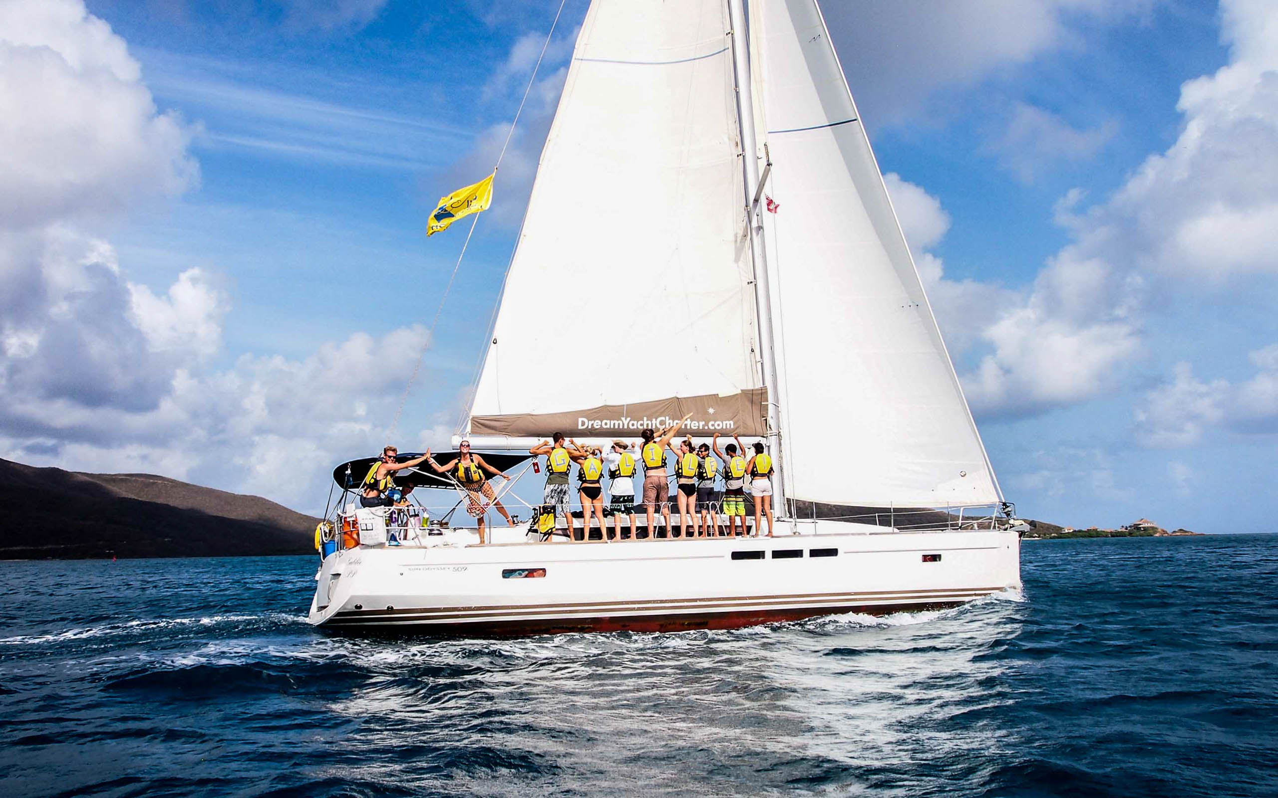 A group of people on a sailboat in the ocean.