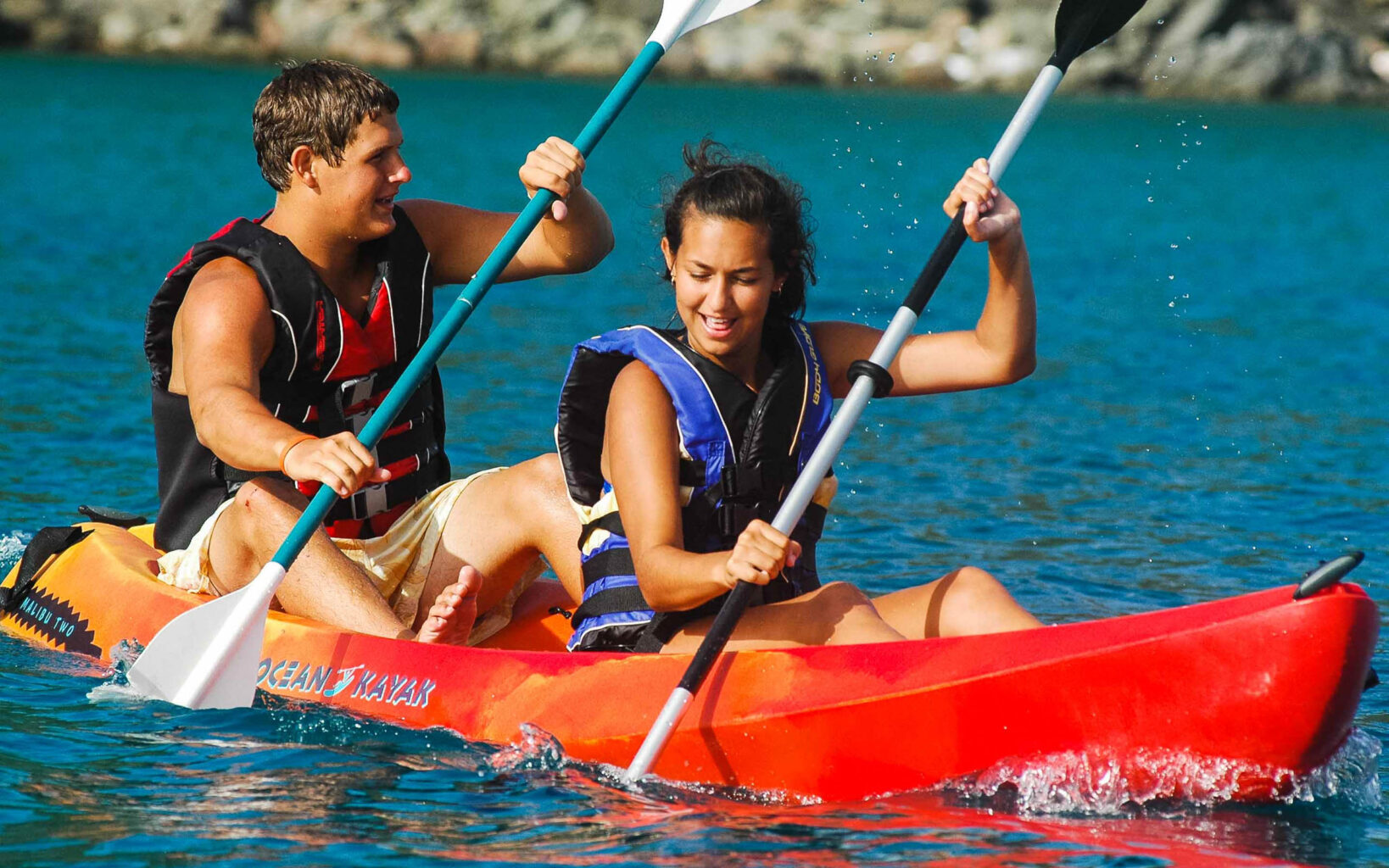 A man and woman are paddling in a red kayak.