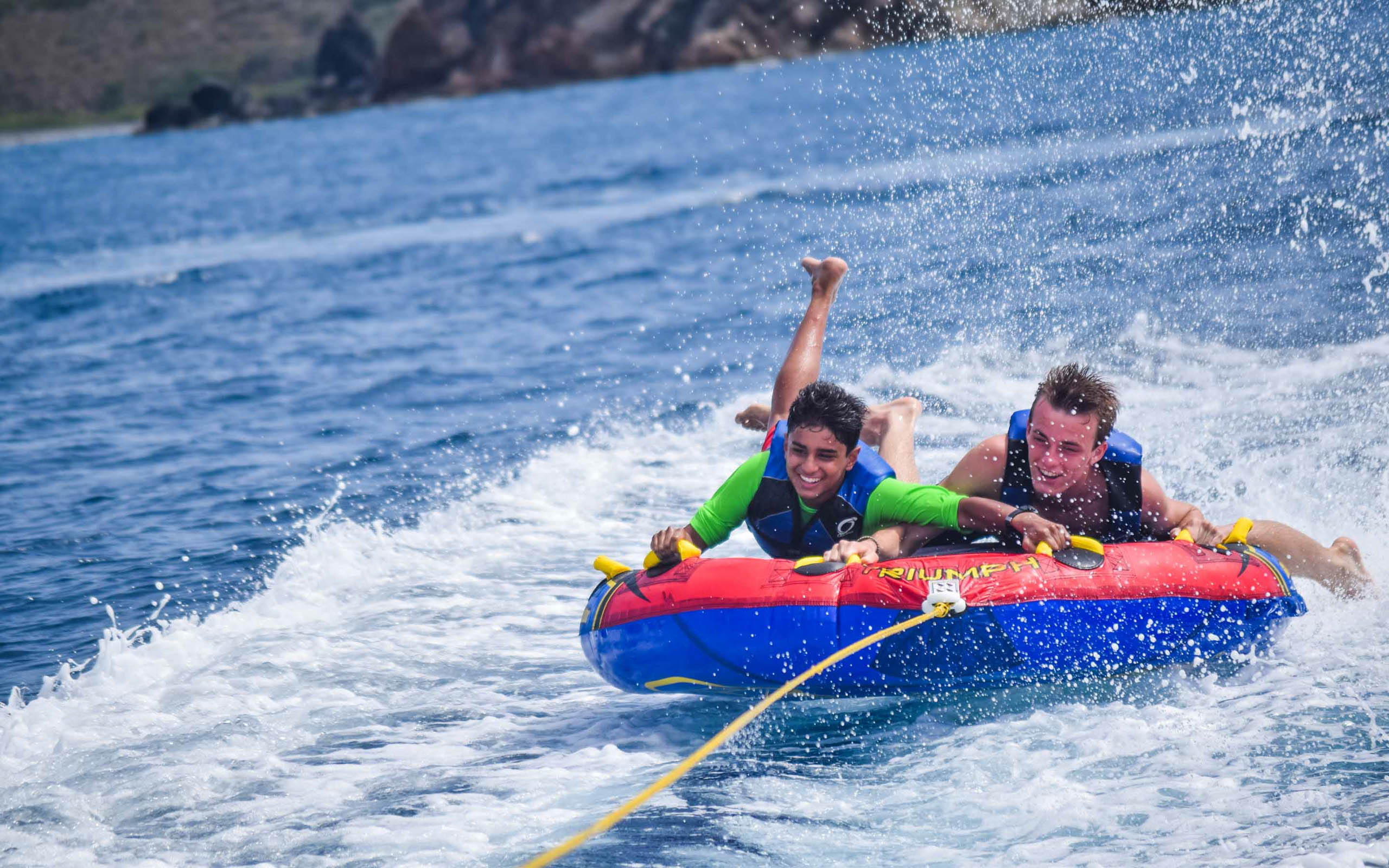 Two people riding on a water tube in the ocean.
