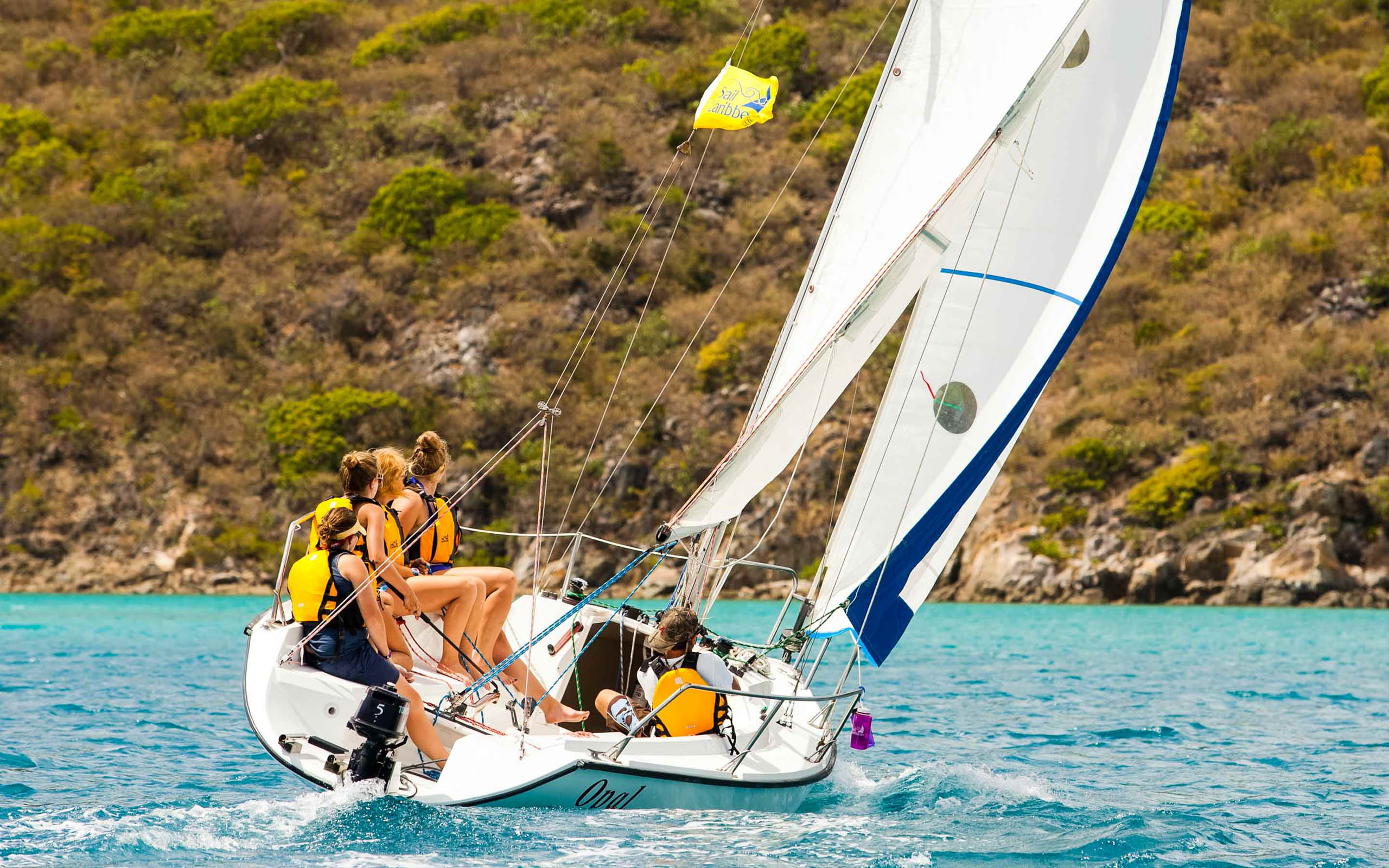 A group of people on a sailboat in the ocean.