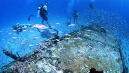A group of scuba divers are swimming around a shipwreck.