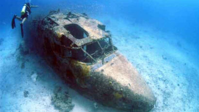 A diver is scuba diving near an old plane.