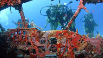 A group of people are scuba diving in the wreck of a ship.