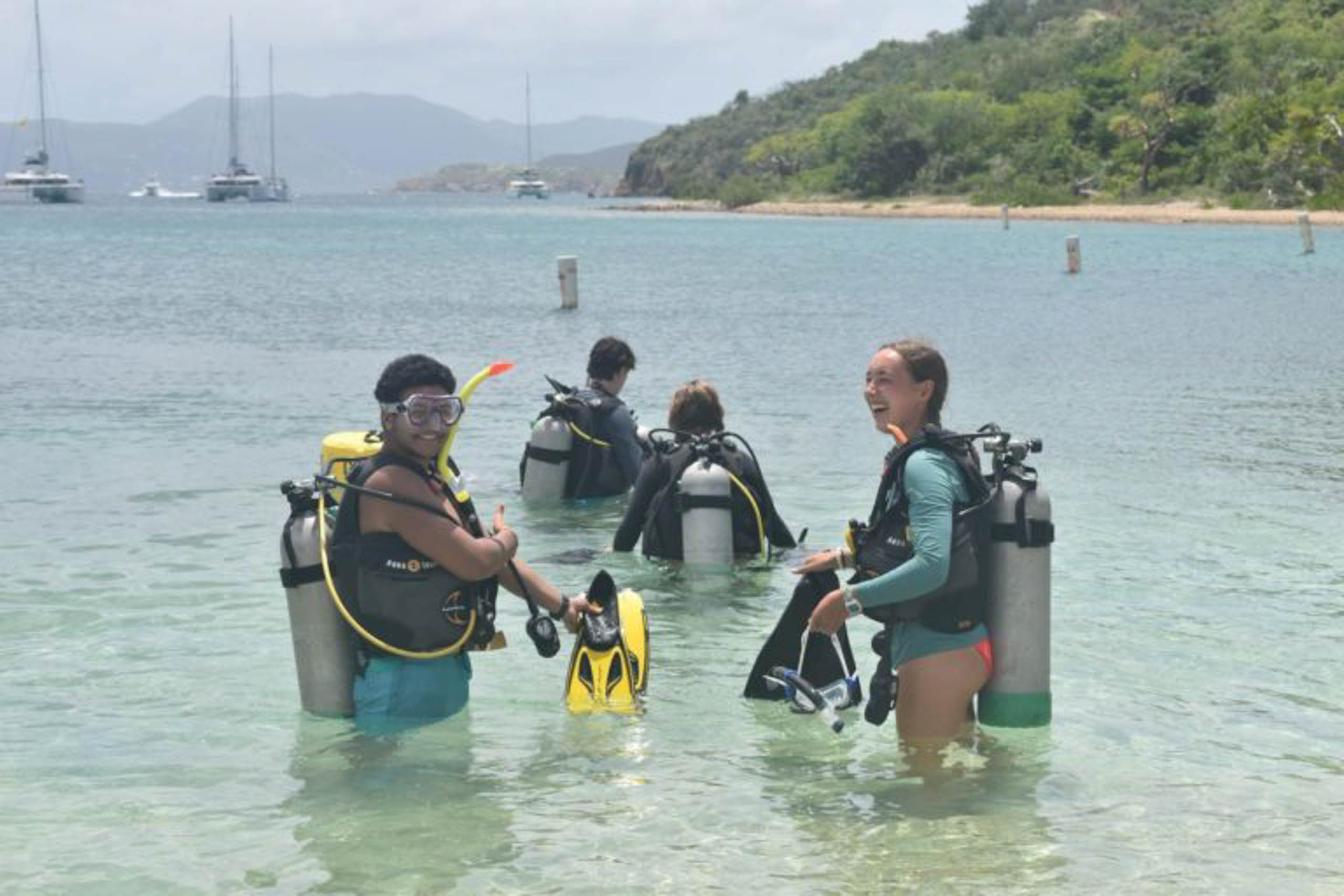 A group of people wearing scuba gear in water.