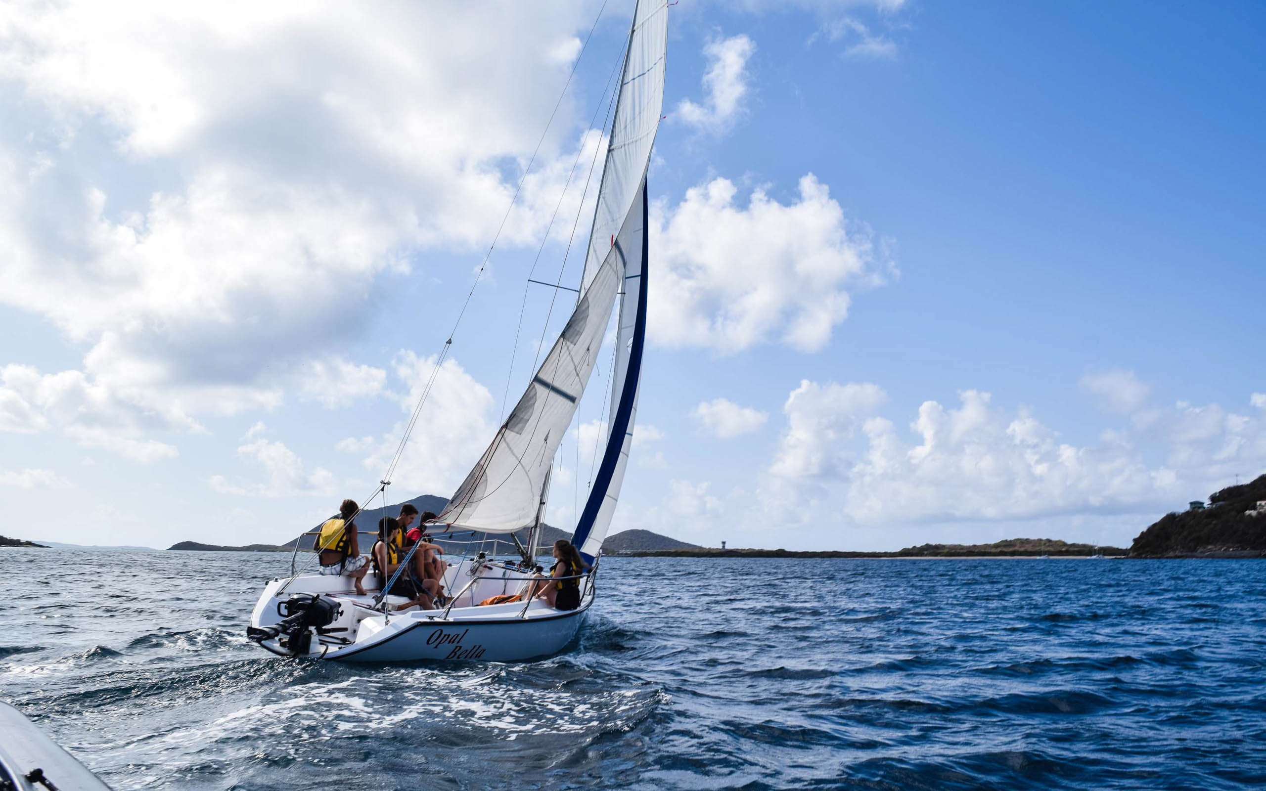 A group of people sailing on a sailboat in the ocean.