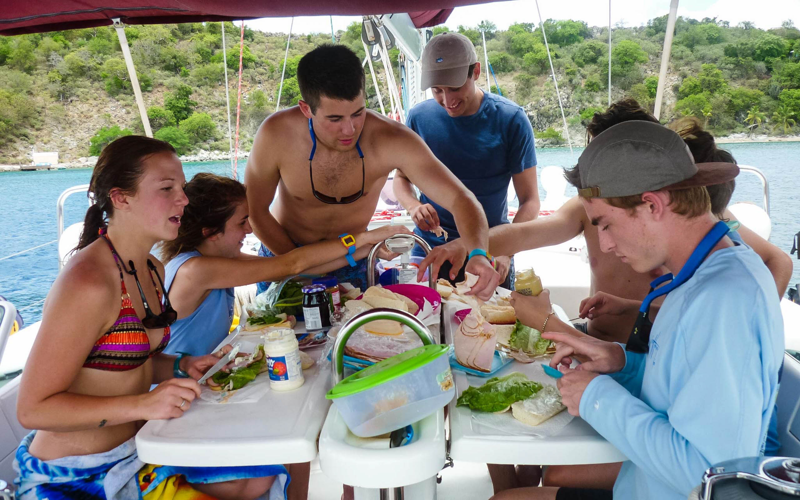 A group of people sitting around a table on a sailboat.