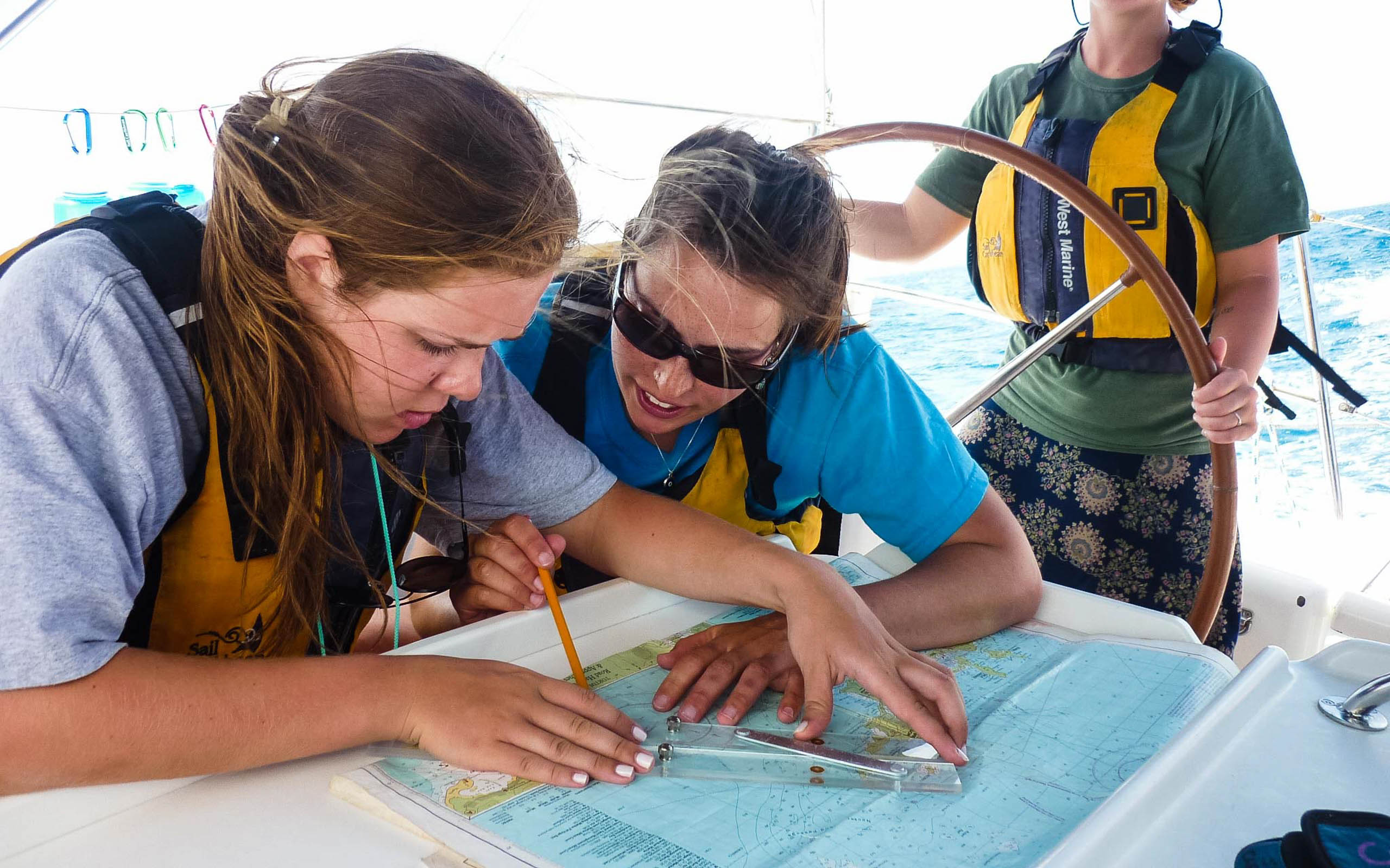 Two women looking at a map on a sailboat.