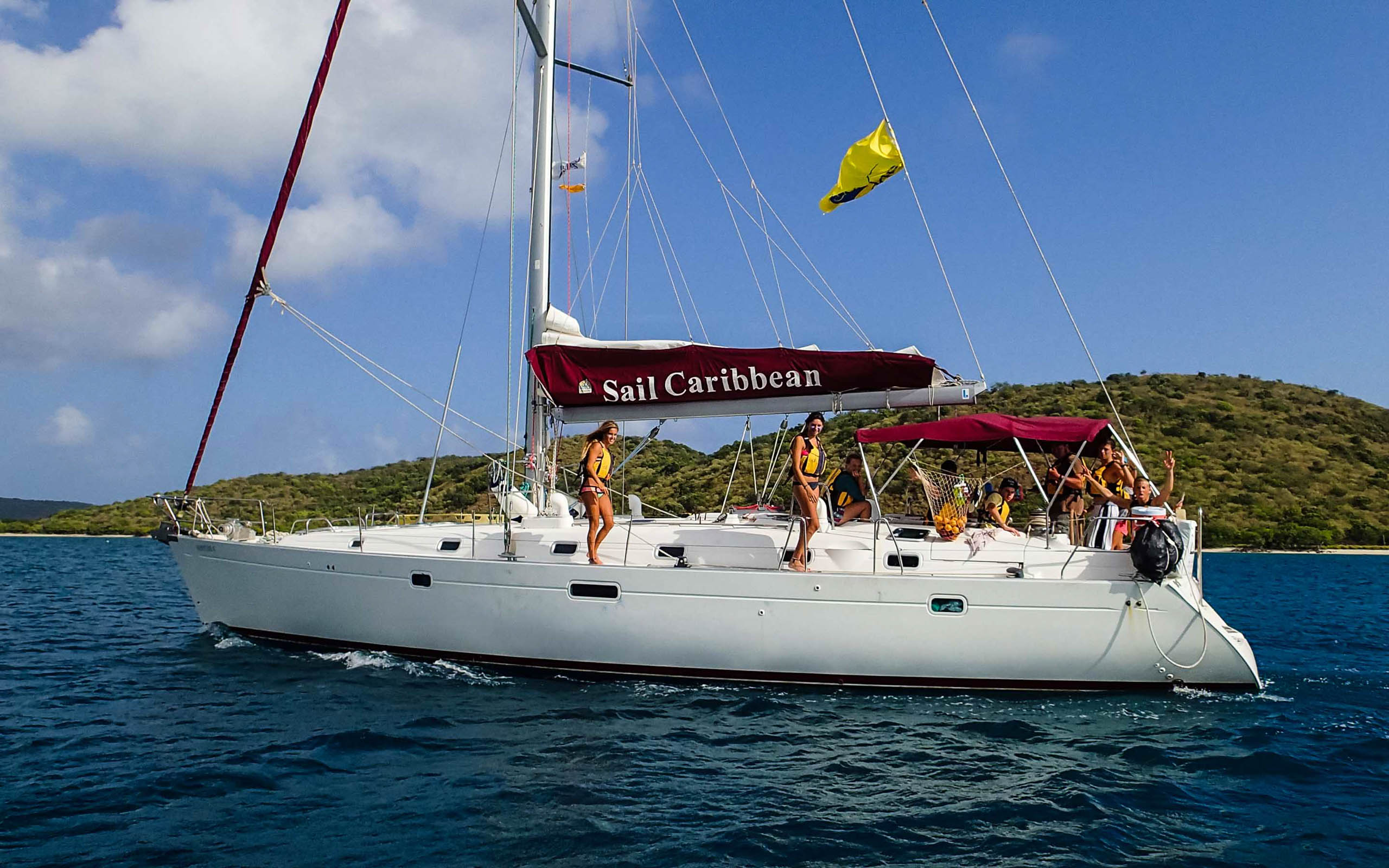 A white sailboat in the ocean with people on it.