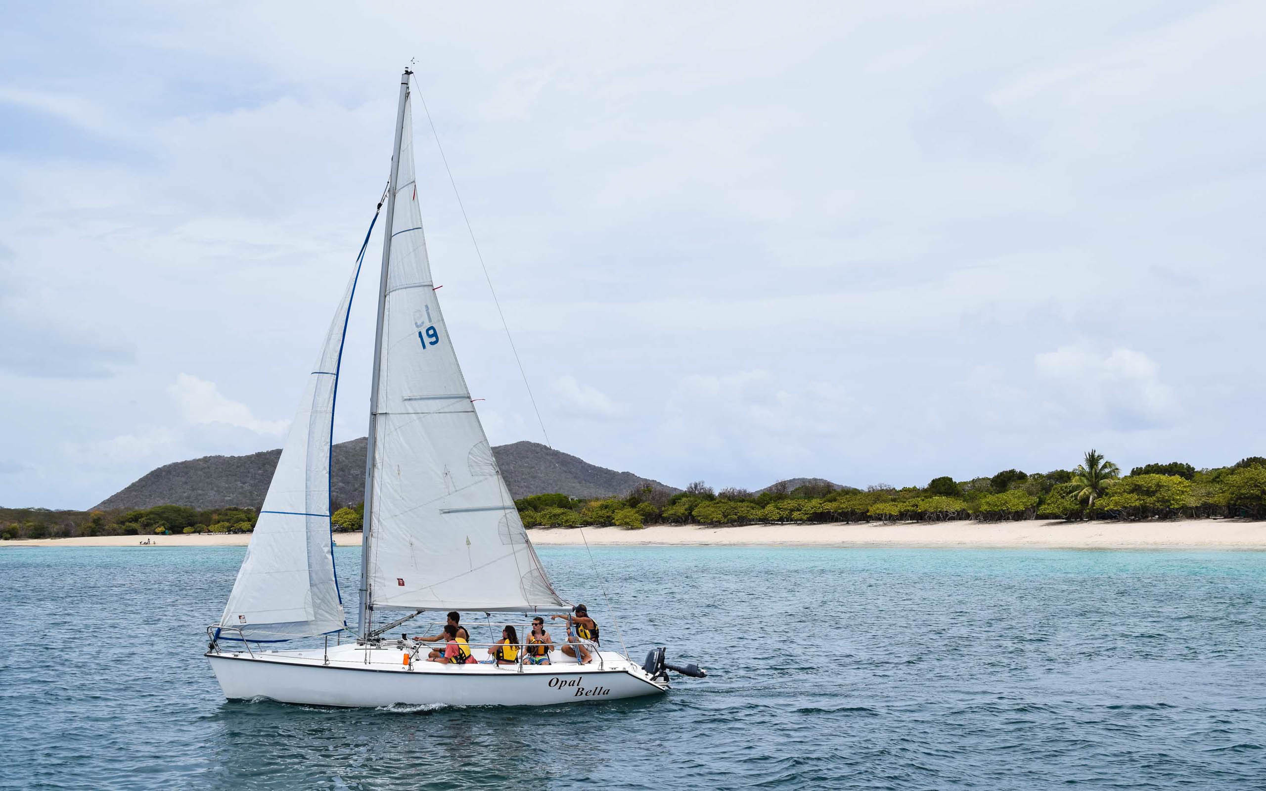 A group of people on a sailboat in the ocean.