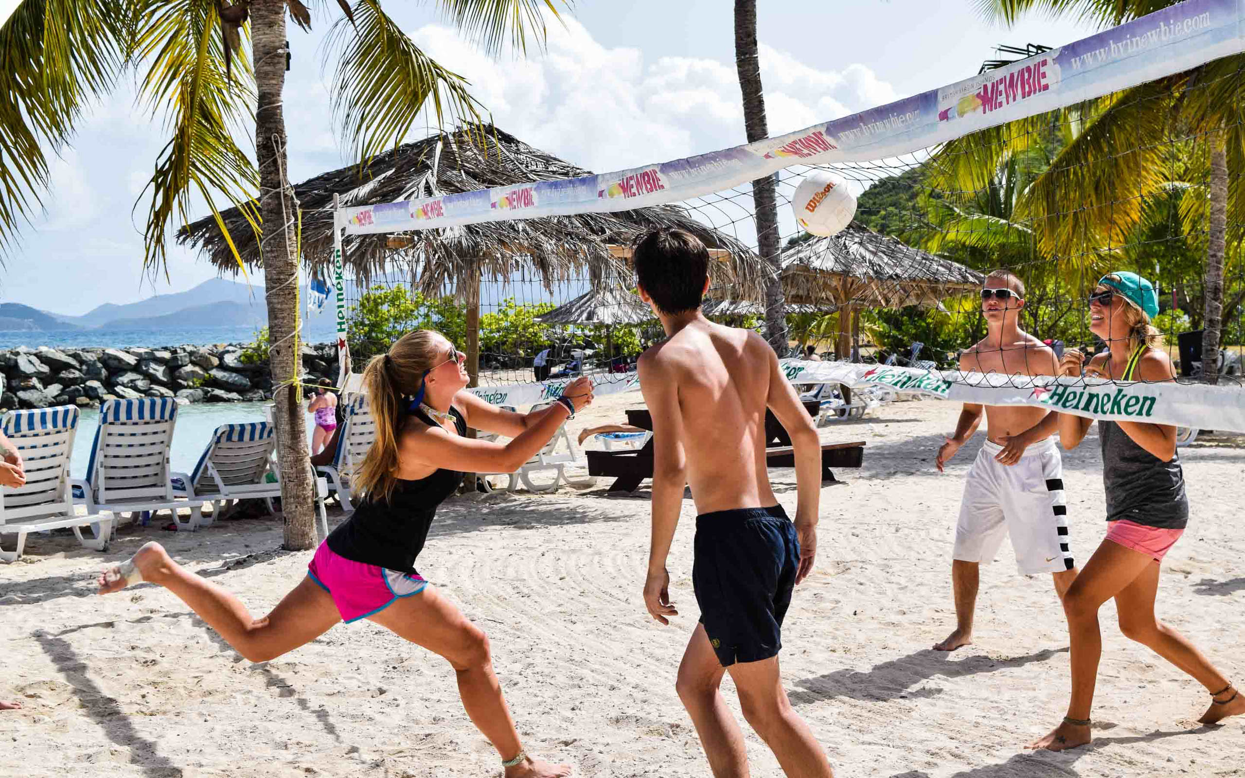 A group of people playing volleyball on the beach.